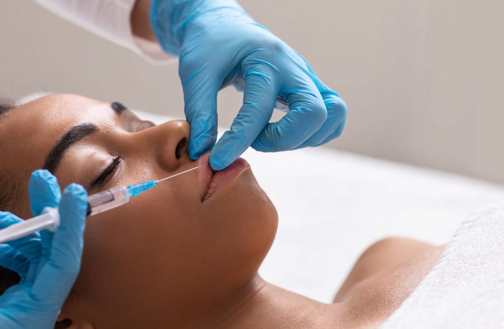 Close-up on a woman's face showing the professional application of lip fillers treatment